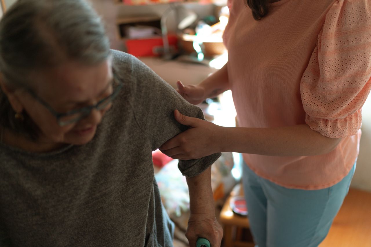 Services Compassionate caregiver helps elderly woman with mobility at home, offering caring support.